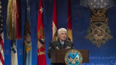 Spc. 5 James C. McCloughan speaks at a podium.