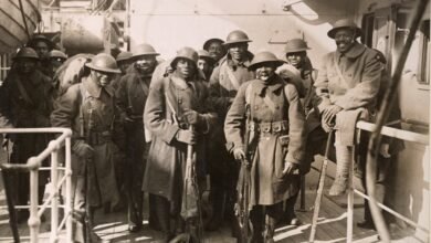 Men wearing military uniforms and holding long guns pose for a group photo aboard a ship.