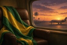 Green and yellow sash draped over an empty chair beside an airport window with a private jet at dusk